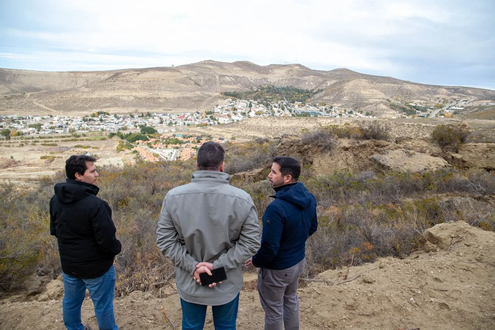 Tres ingenieros y funcionarios supervisan el terreno del cerro Hermitte con vista al barrio Médanos.