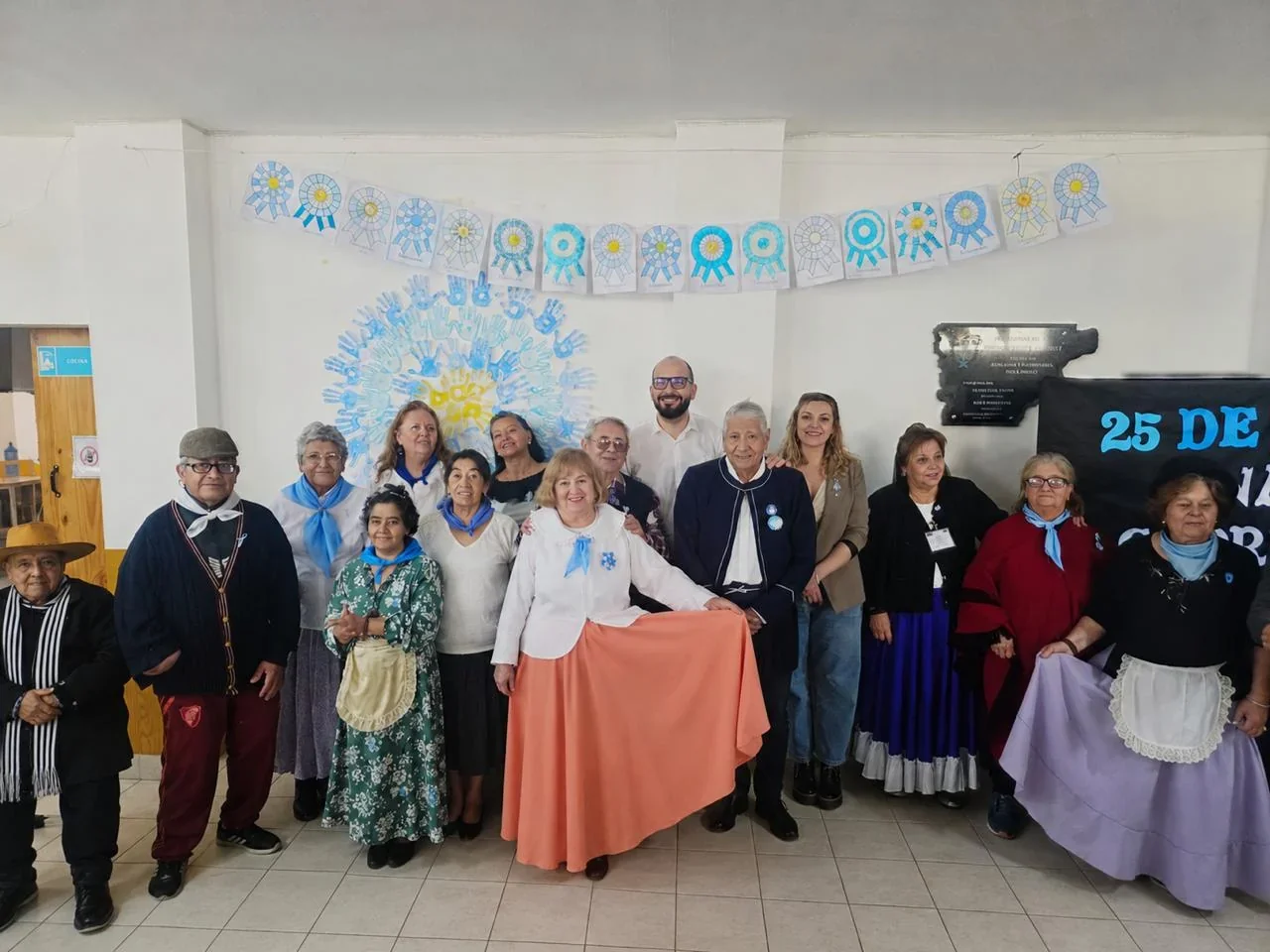 Grupo de personas mayores y coordinadores en el Centro de Día Papa Francisco celebrando el 25 de Mayo.