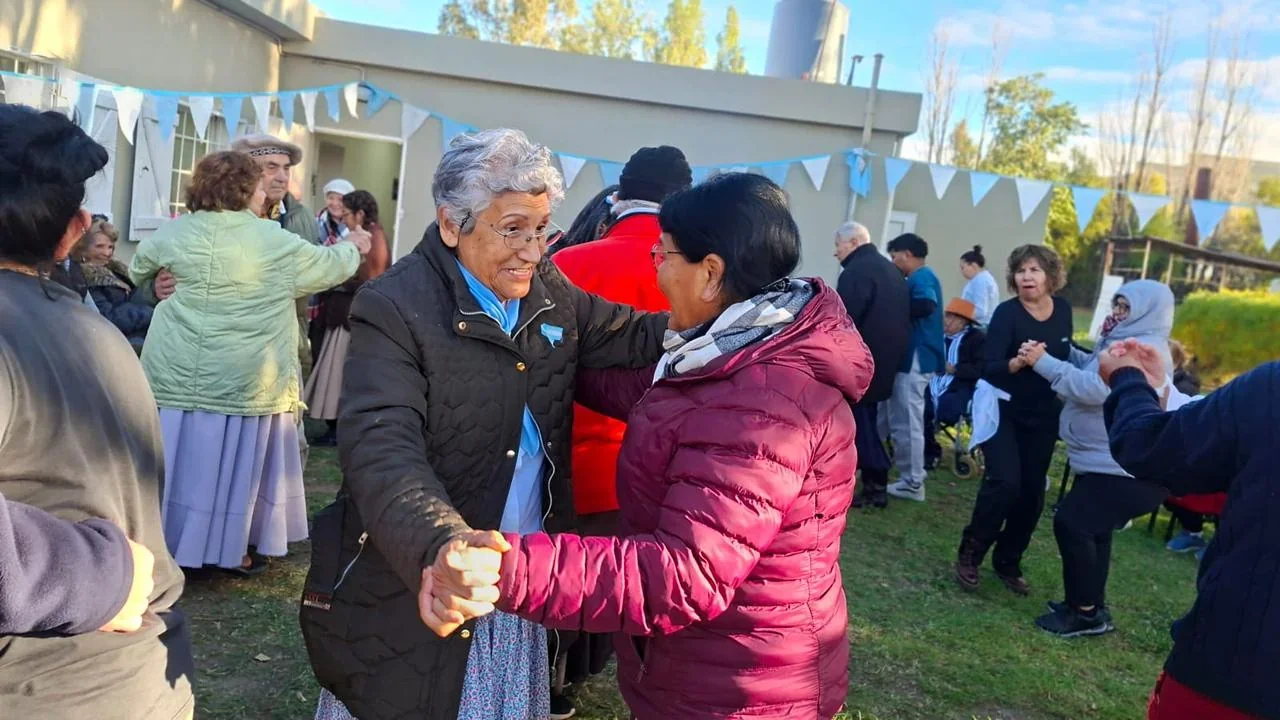 Personas mayores bailando en el jardín del Centro de Día Papa Francisco durante el festejo del 25 de Mayo.