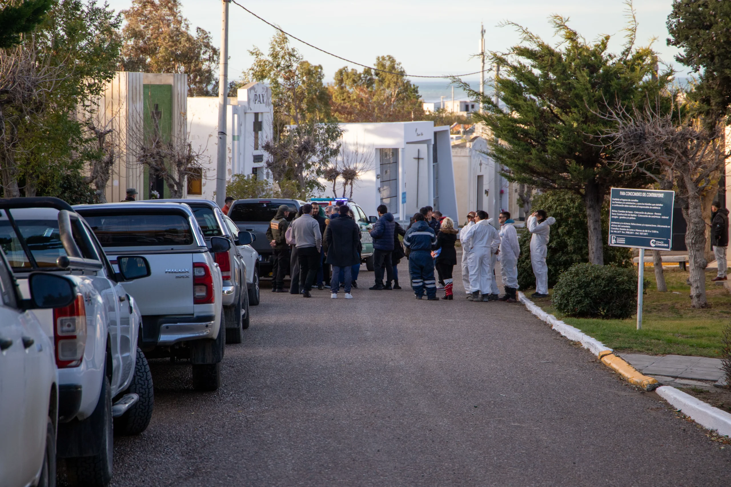 Personal forense con trajes blancos y efectivos policiales en el Cementerio Oeste de Comodoro Rivadavia.
