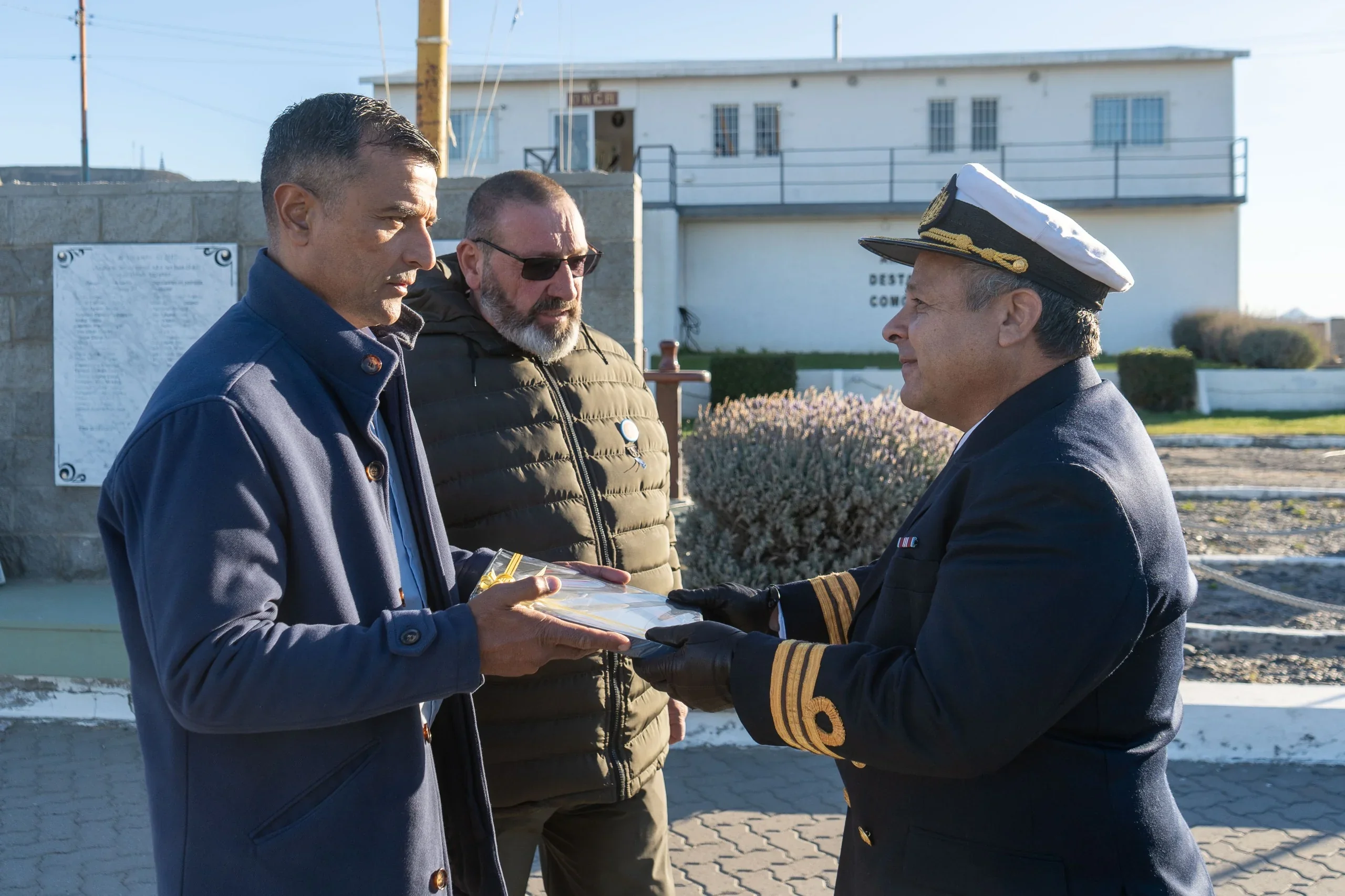 Representantes municipales y un oficial de la Armada Argentina durante la entrega de una placa en la Plaza de Armas.