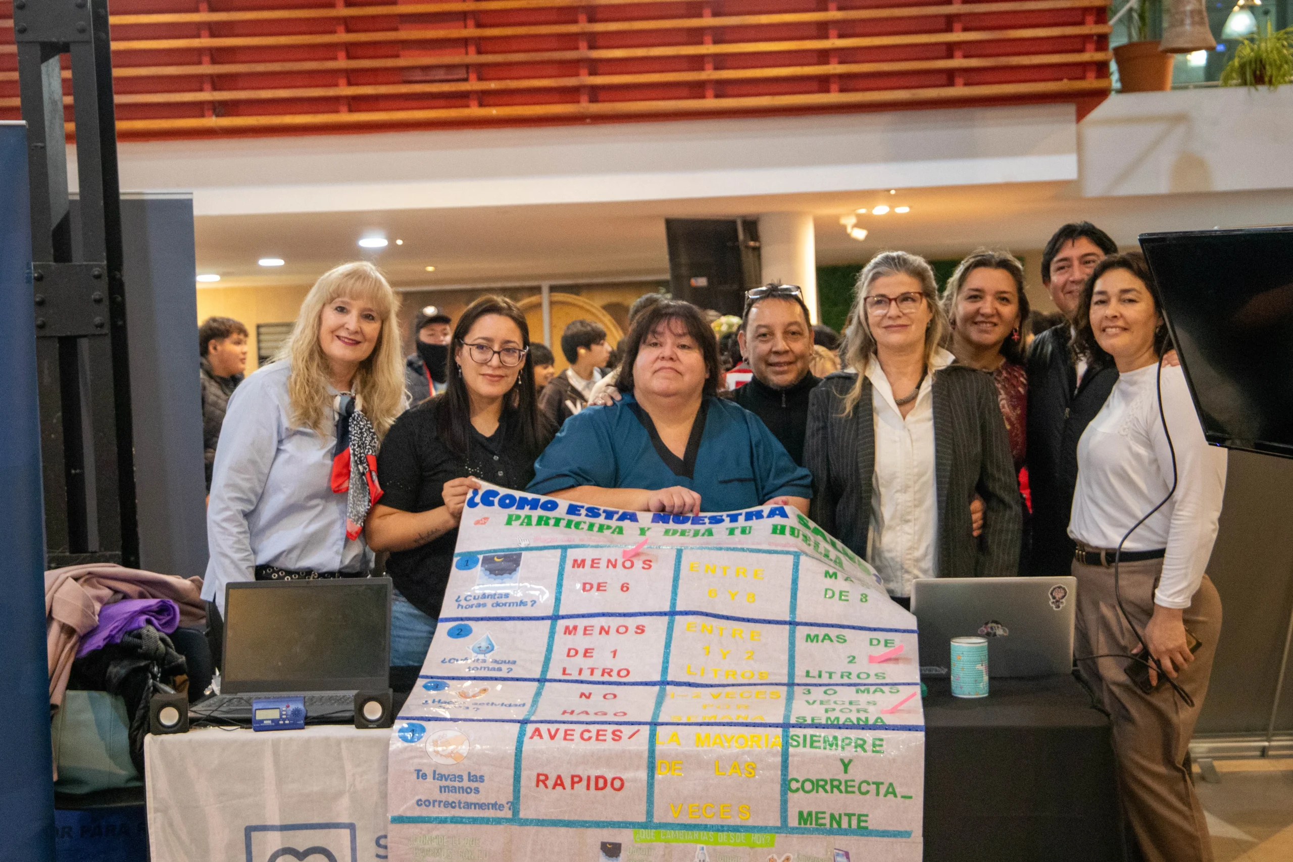 Grupo de personas posando detrás de un panel informativo sobre salud en la 7° Feria Integradora de Salud.