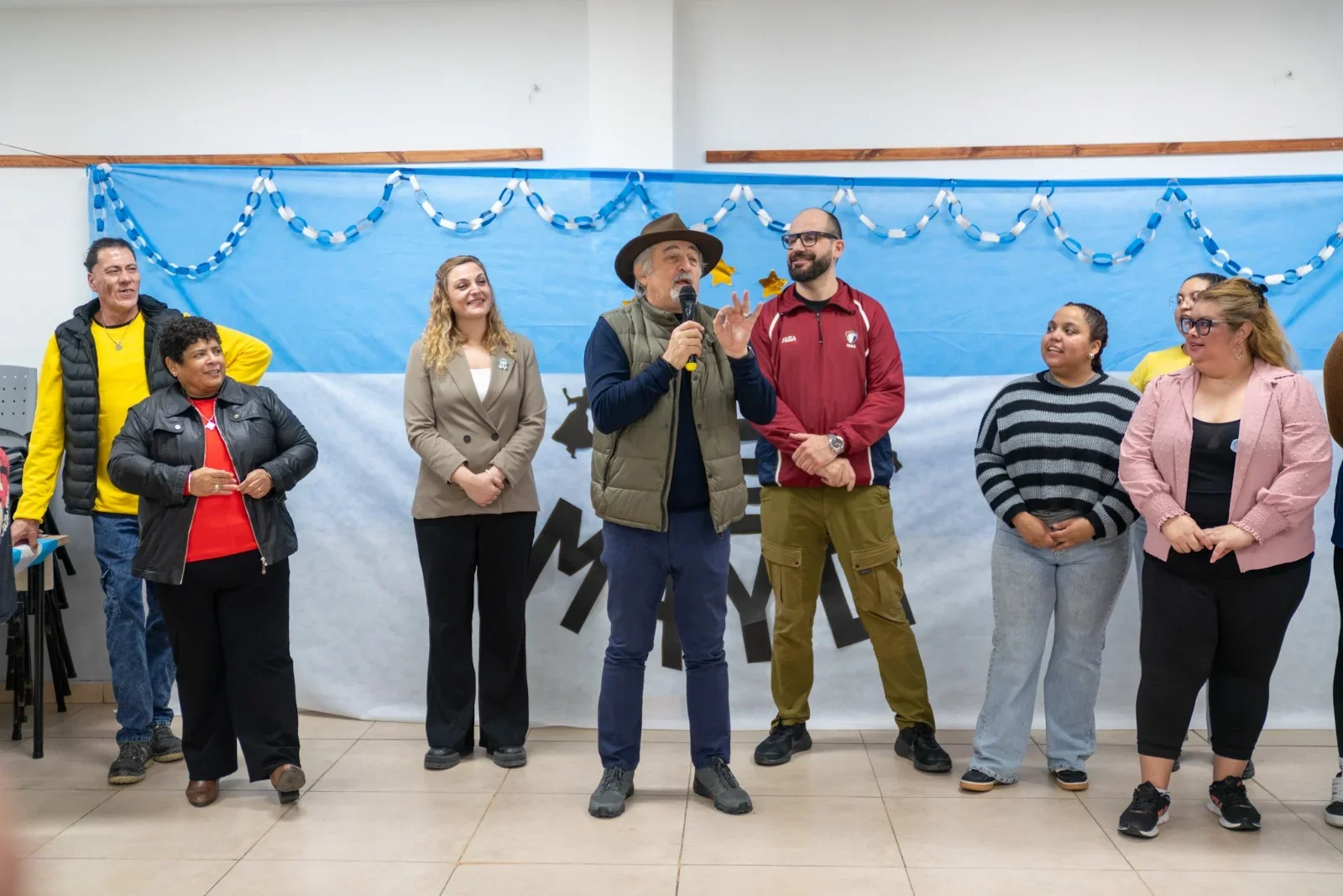 El intendente Othar Macharashvili habla con un micrófono frente a un grupo de personas y banderas argentinas.