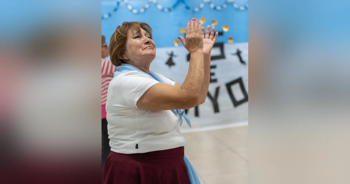 Comodoro Rivadavia: Othar celebró el 25 de Mayo con adultos mayores Mujer adulta mayor con vestimenta blanca y celeste aplaudiendo en la celebración del 25 de Mayo en Comodoro Rivadavia.