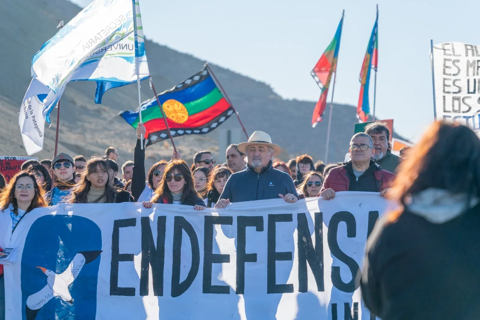 Manifestantes en Comodoro Rivadavia sostienen una pancarta que dice 'EN DEFENSA' durante la Marcha Federal Universi