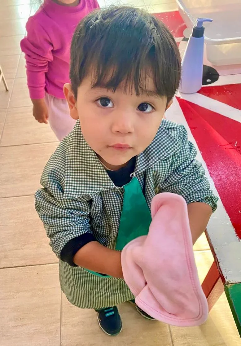 Niño en un Centro de Primera Infancia de Puerto Madryn sosteniendo una toalla rosa durante un taller de salud.