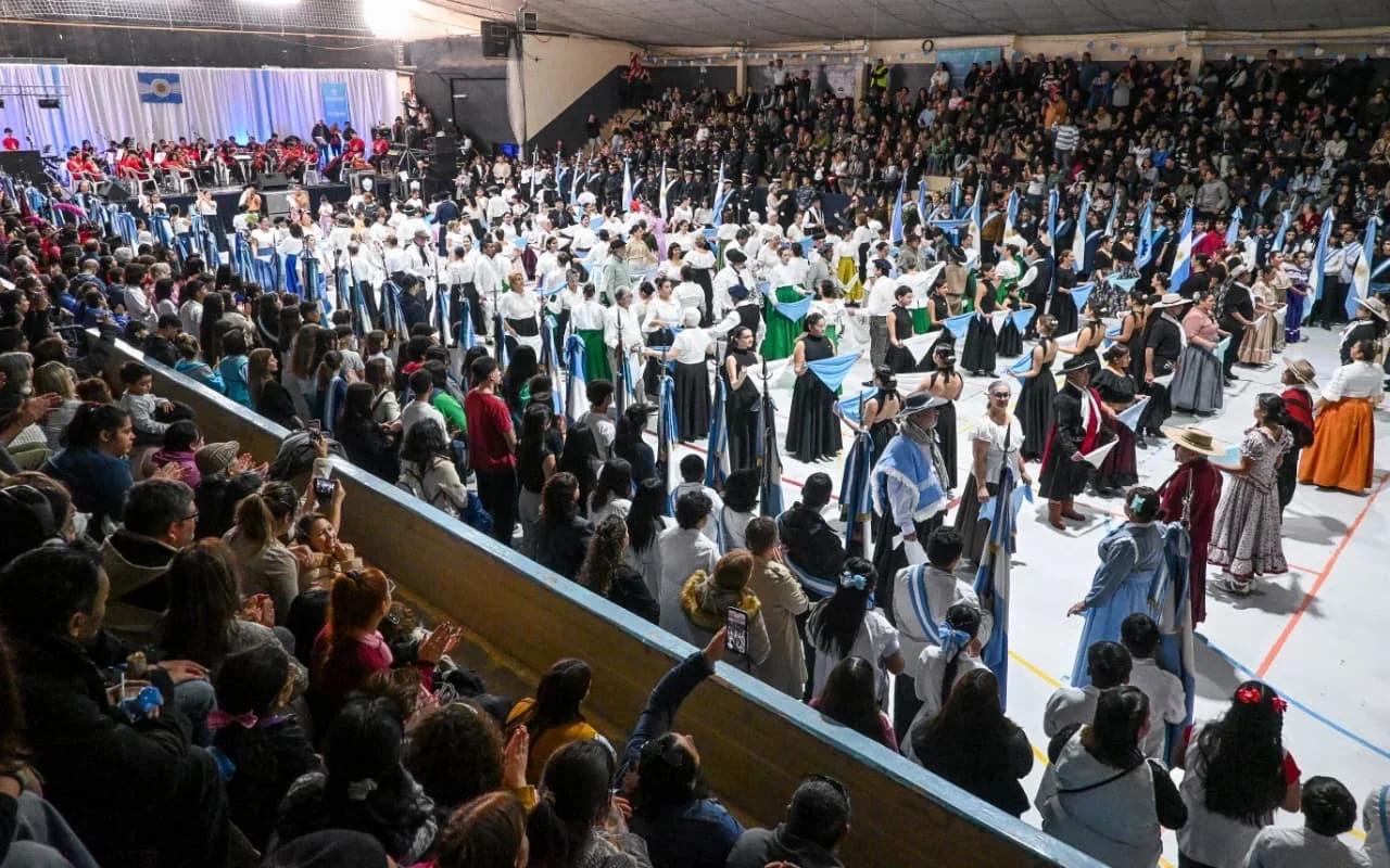 Personas vestidas con trajes coloniales y banderas argentinas en un acto por el 25 de Mayo en Puerto Madryn.