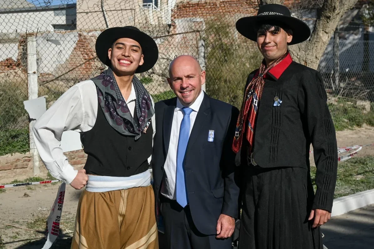 El intendente Gustavo Sastre posa junto a dos jóvenes vestidos con trajes típicos gauchos en Puerto Madryn.