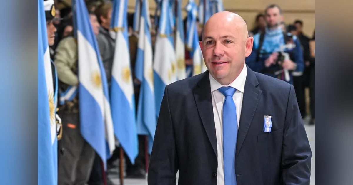 Puerto Madryn: Sastre encabezó los actos por el 25 de Mayo y llamó a la unidad El intendente Gustavo Sastre con traje y corbata azul frente a banderas argentinas en el acto del 25 de Mayo.