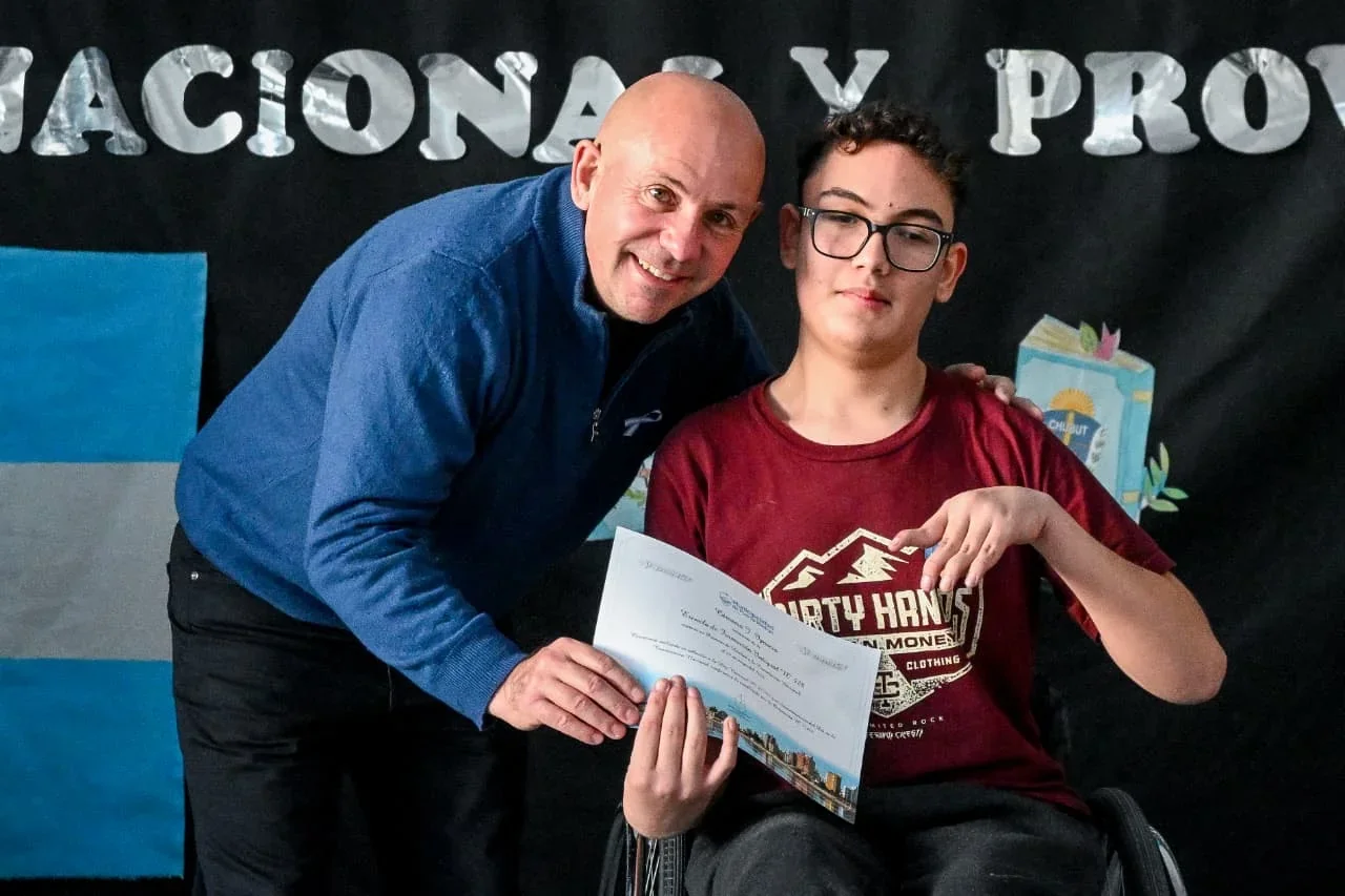 El intendente Gustavo Sastre junto a un alumno de la Escuela N° 528 sosteniendo el diploma de lealtad a la Constitución.
