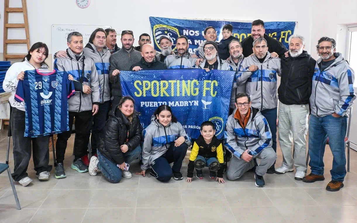 El intendente Gustavo Sastre y miembros del Sporting Fútbol Club posan con camisetas y banderas del equipo en Madryn.