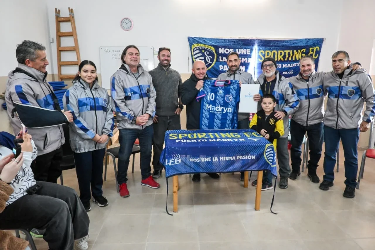 El intendente Gustavo Sastre y miembros del Sporting Fútbol Club posan con una camiseta y el documento de tierras.