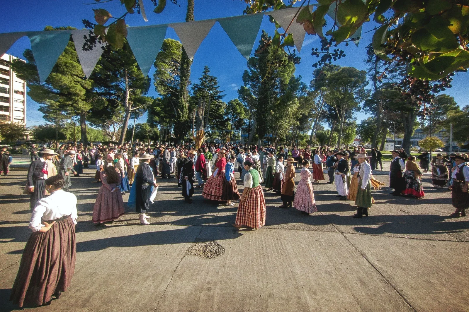 Personas vestidas con trajes típicos coloniales durante el acto por el 216° aniversario de la Revolución de Mayo en Rawson.