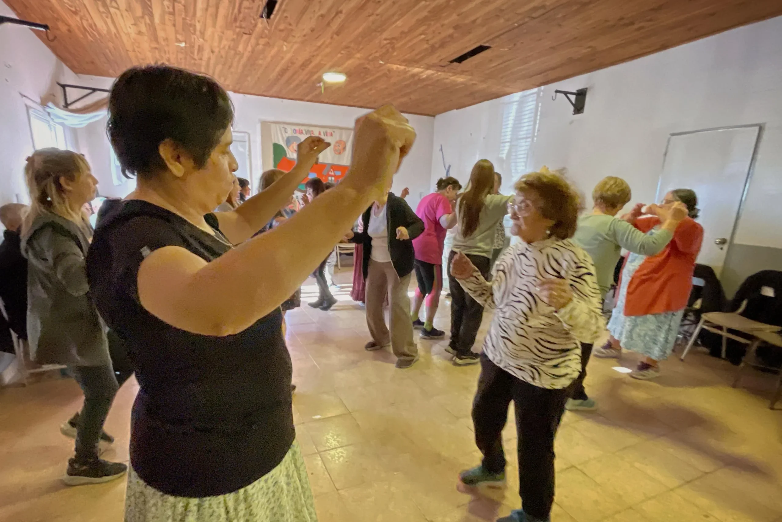 Personas mayores bailando folclore en el Centro Comunitario del barrio 3 de Abril, en Rawson.