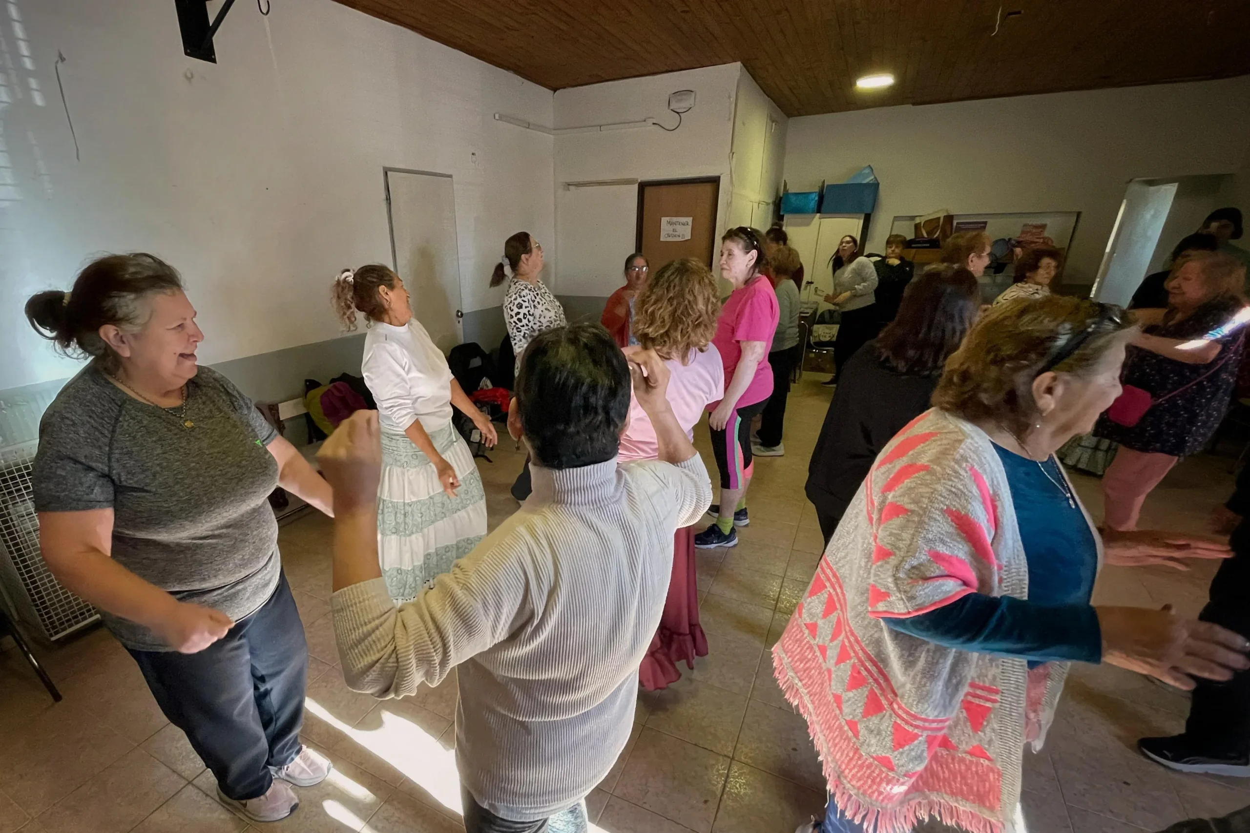 Personas mayores bailando folclore en el Centro Comunitario del barrio 3 de Abril, Rawson.