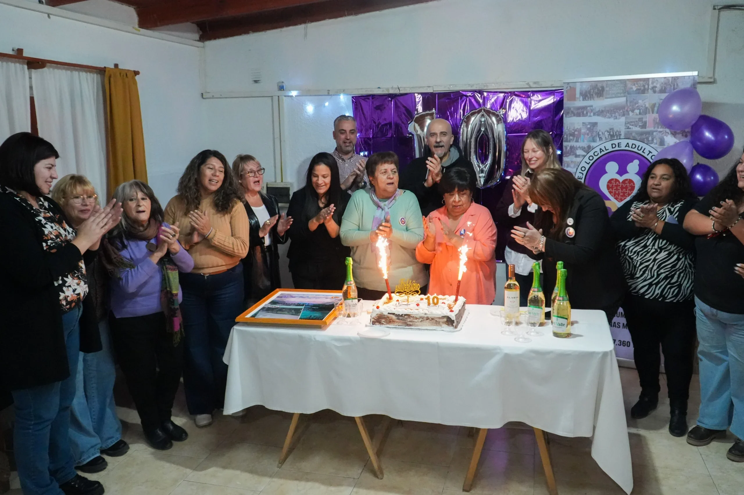 Integrantes y autoridades del Consejo Local de Adultos Mayores de Rawson celebrando el 10° aniversario con una torta.