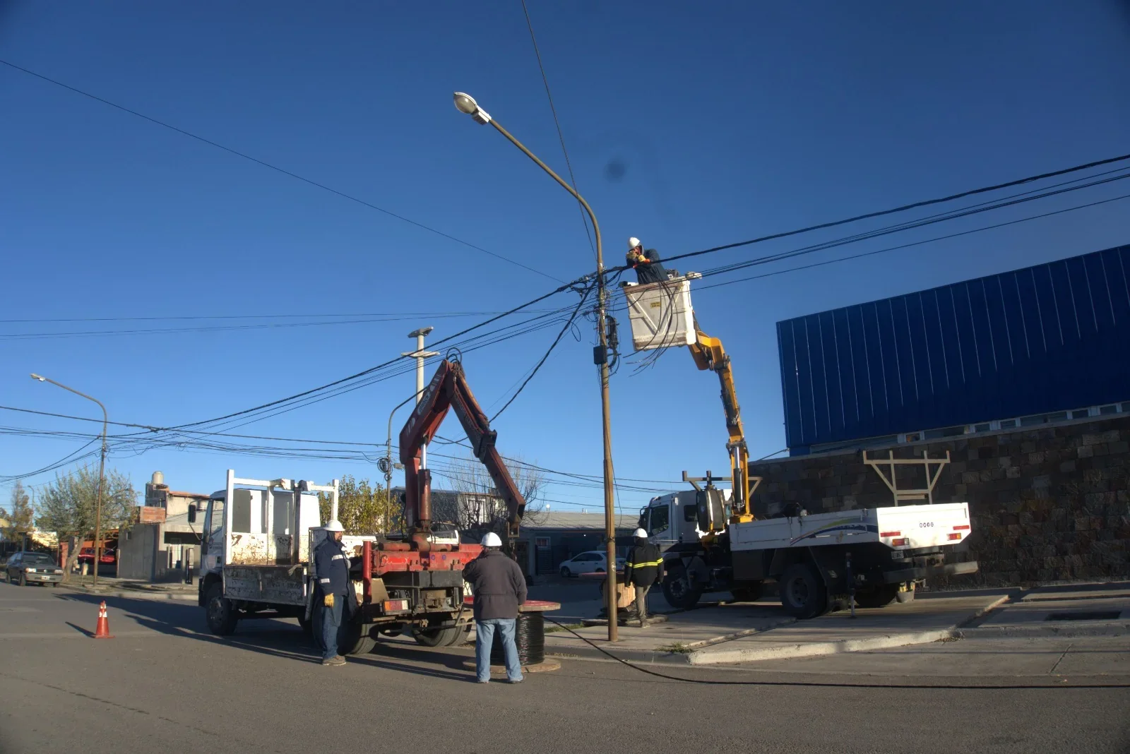 Técnicos de la Cooperativa de Rawson realizando trabajos en el tendido eléctrico de Chacra 8 con camiones grúa.