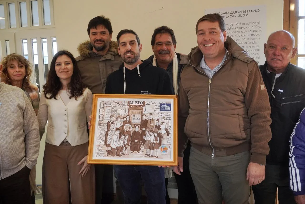 El intendente Damián Biss y un grupo de personas sostienen un cuadro del Museo Regional Salesiano de Rawson.