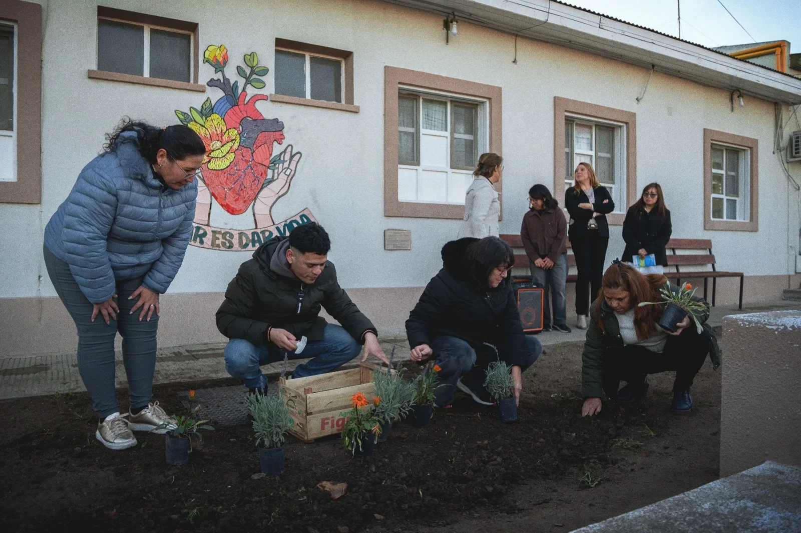 Personas plantando vegetación en la Plazoleta por la Vida, frente al mural "Donar es Dar Vida" del Hospital
