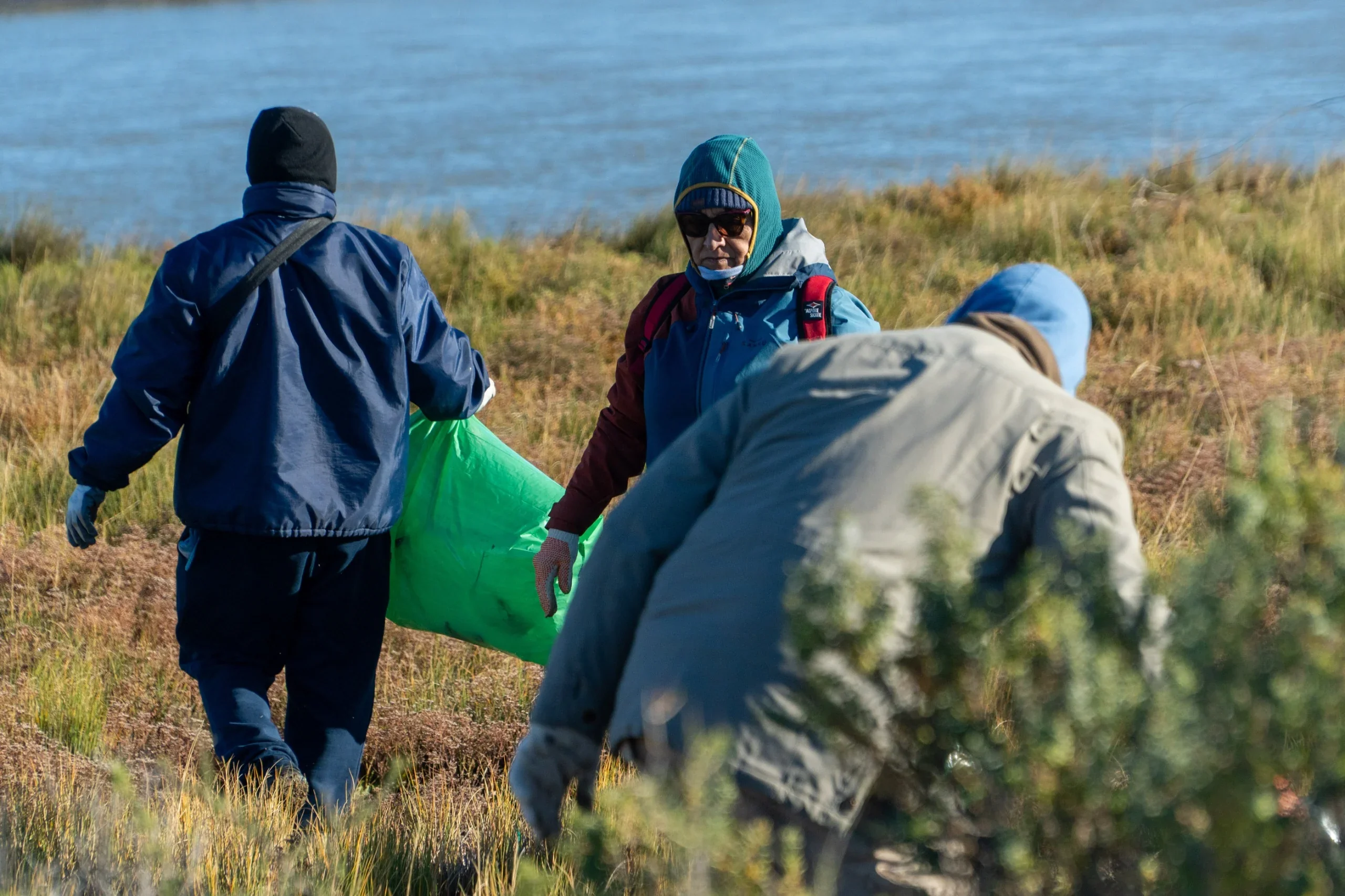 Vecinos recolectando residuos en bolsas verdes durante la jornada de plogging en el sector de El Elsa, Rawson.
