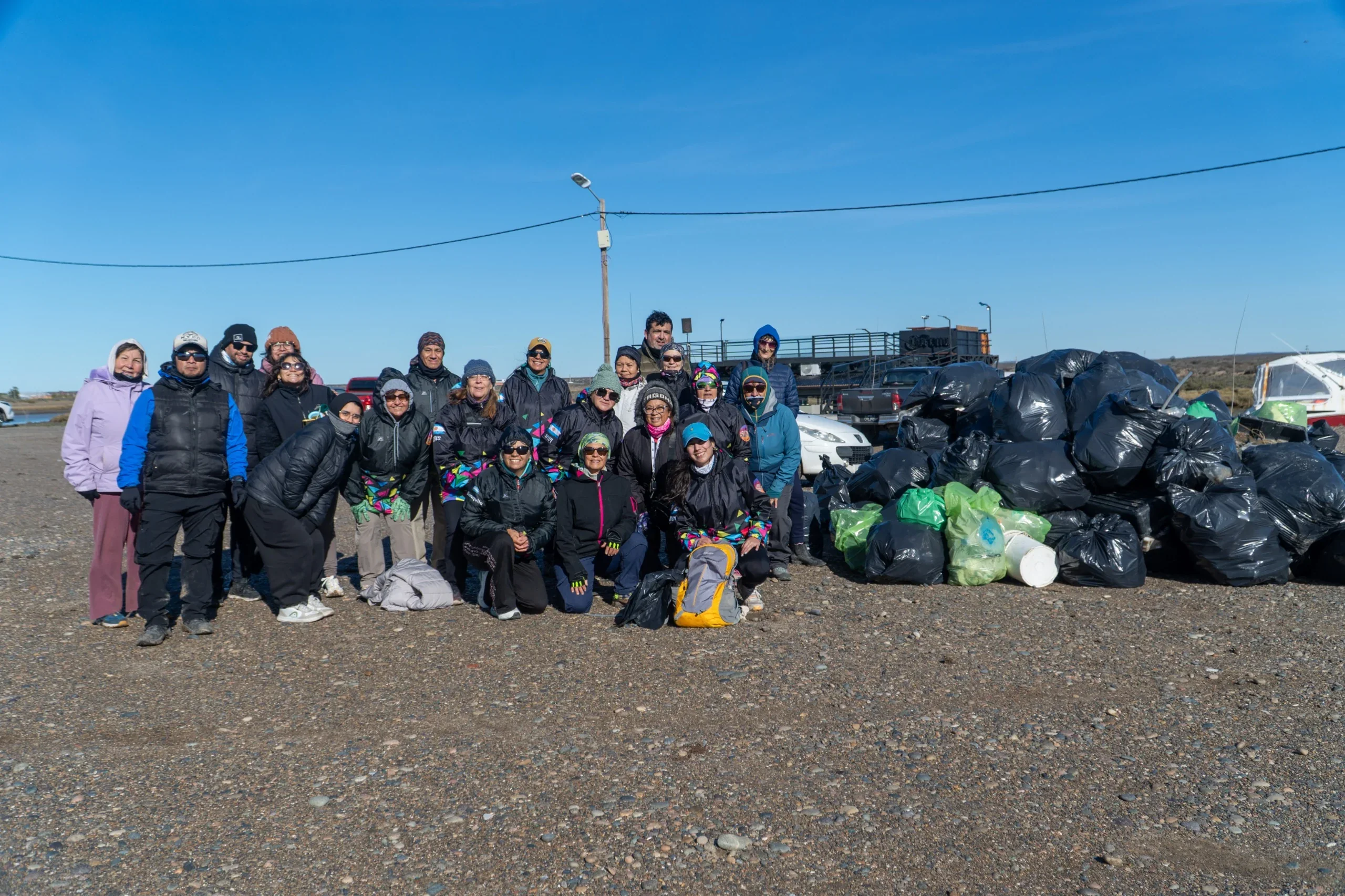 Grupo de vecinos y voluntarios posan junto a bolsas de residuos recolectadas durante el plogging en El Elsa, Rawson.