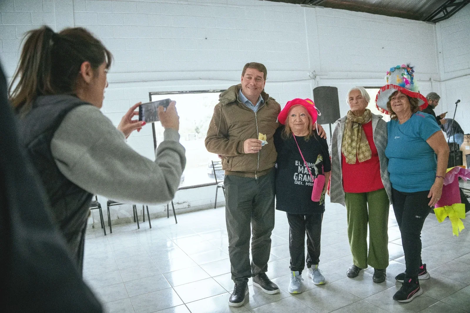 El intendente Damián Biss junto a tres adultos mayores de la Colonia Recreativa de Rawson mientras alguien les toma una foto.