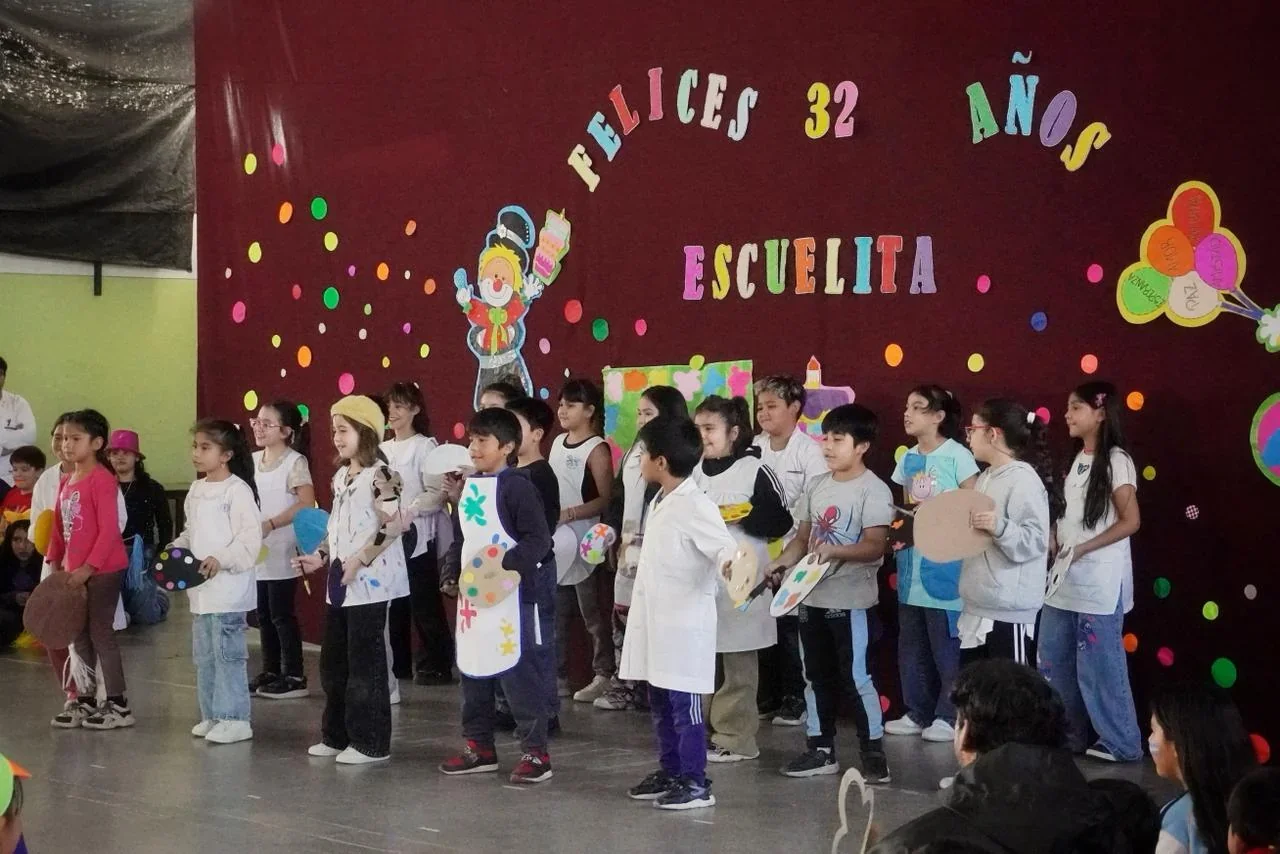 Estudiantes de la Escuela N° 202 de Rawson realizan presentaciones artísticas frente a un cartel de 32° aniversario.