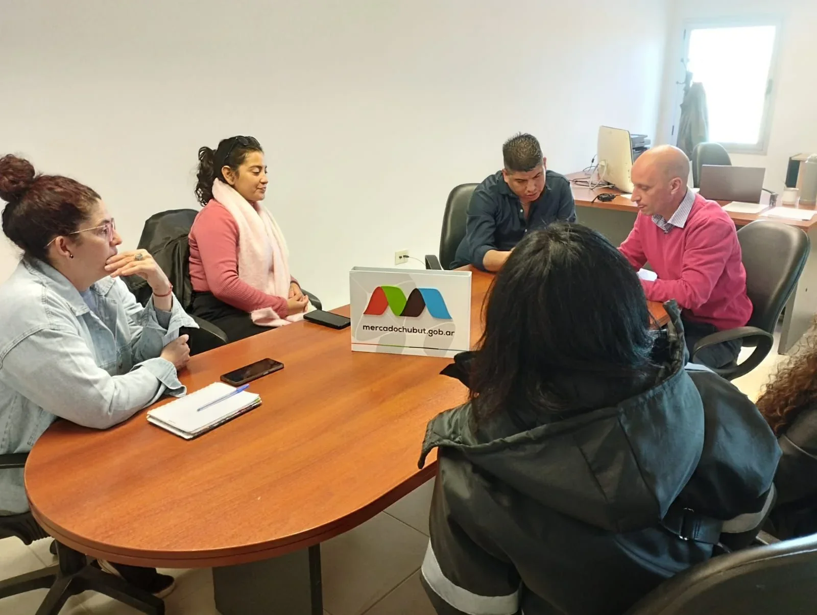 Reunión entre autoridades del Municipio de Rawson y el Mercado Concentrador Chubut alrededor de una mesa de oficina.