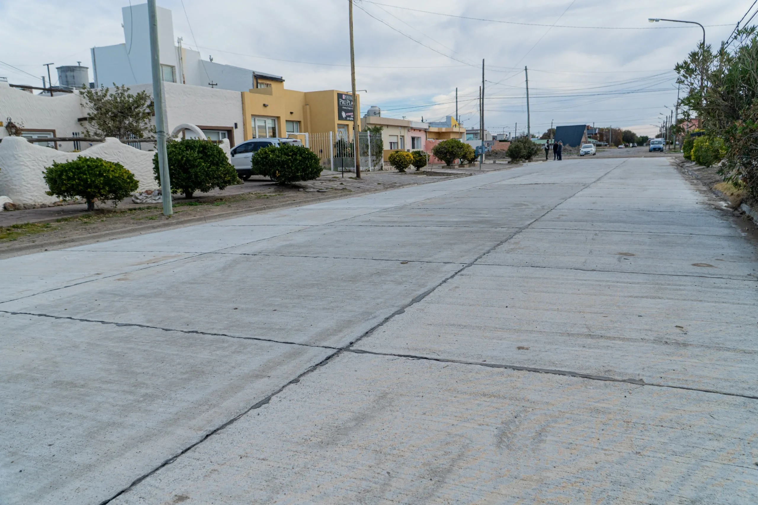 Vista de la calle Canónigo Vivaldi recién pavimentada en Playa Unión, Rawson, con casas y vegetación a los costados.