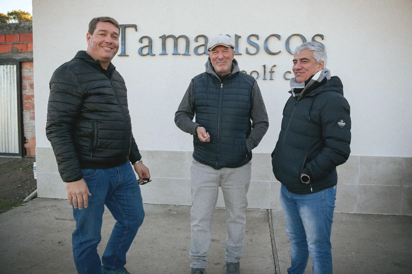 El intendente Damián Biss y Rolando Iralde junto a un golfista frente al logo de Tamariscos Golf Club en Rawson.
