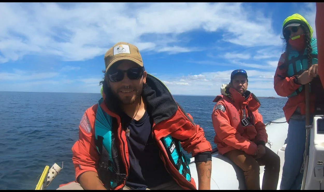 Lautaro Comesaña y dos acompañantes con chalecos salvavidas a bordo de una embarcación en el mar de Camarones.