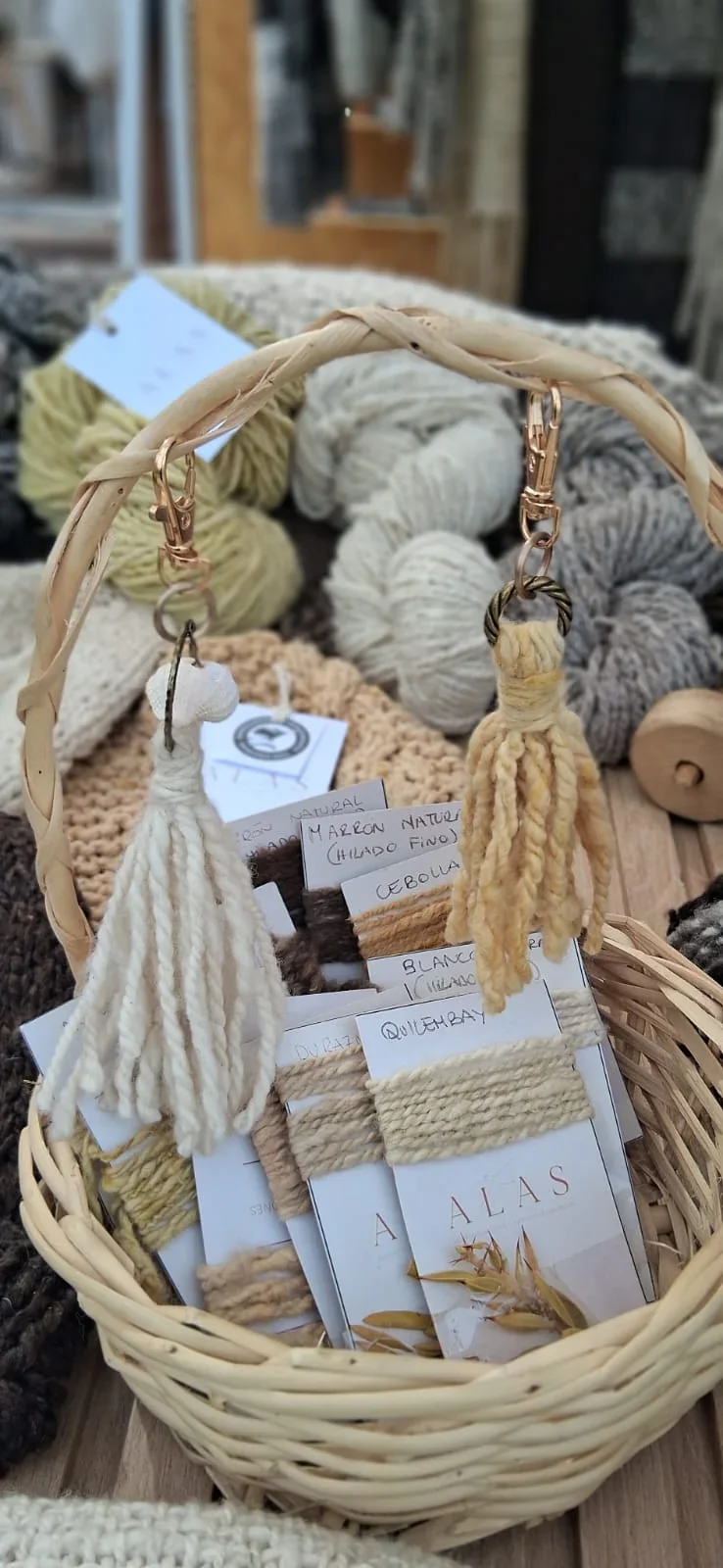 Canasta de mimbre con hilos de lana merino y etiquetas del grupo de tejedoras ALAS de Camarones en la Bioferia.