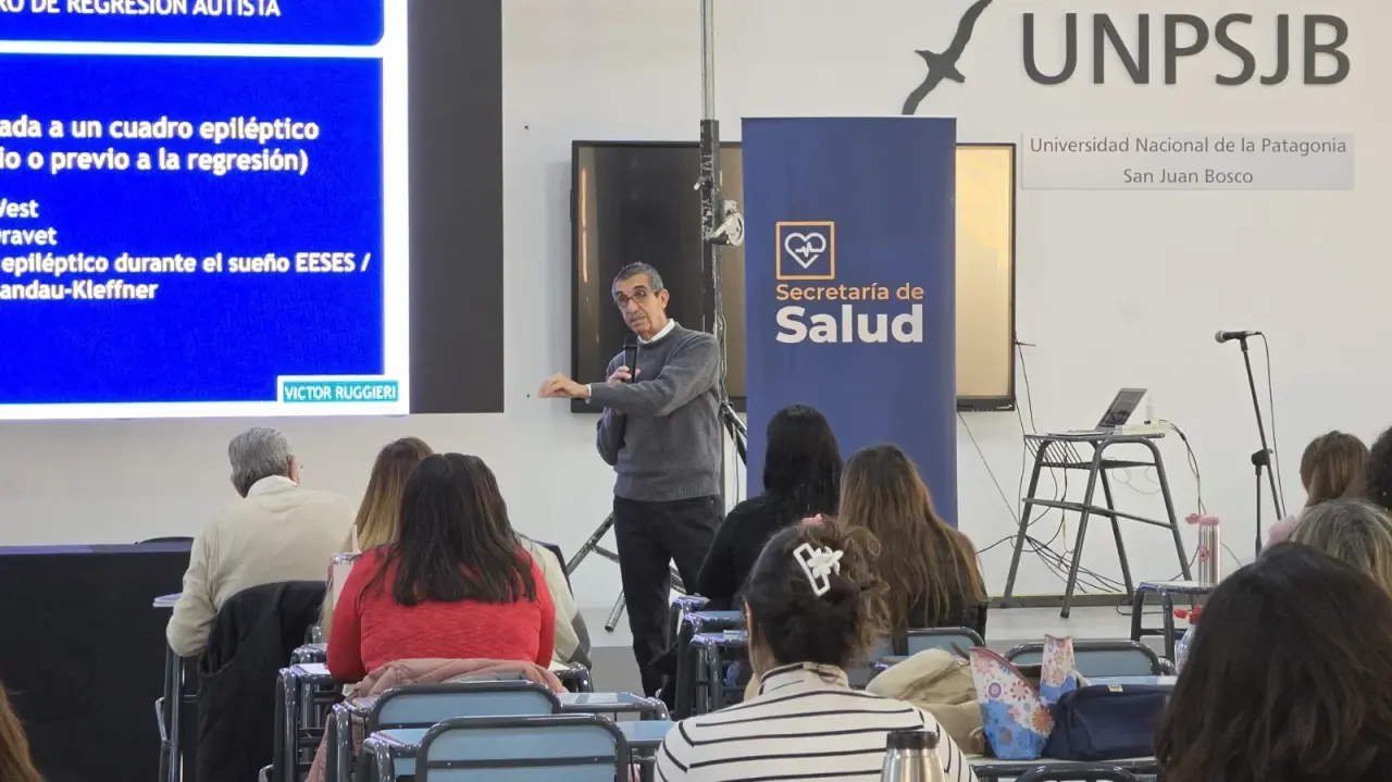 Expositor impartiendo una charla sobre autismo frente a una audiencia en la Universidad Nacional de la Patagonia.