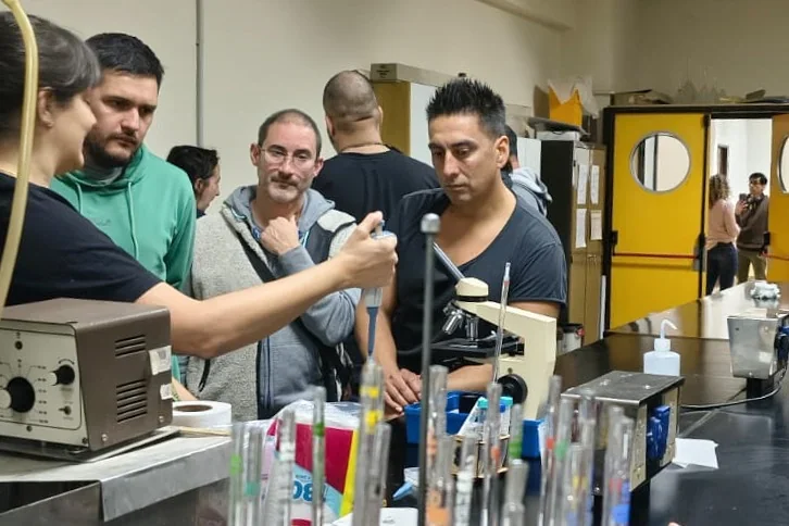 Productores cerveceros en un laboratorio observando el uso de una pipeta y tubos de ensayo durante la capacitación.