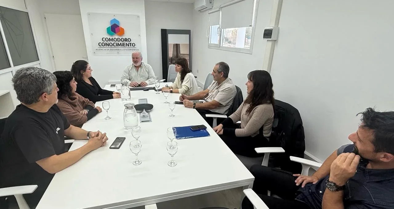 Reunión de profesionales de la Agencia Comodoro Conocimiento, UNPSJB e INBIOP en una oficina blanca.