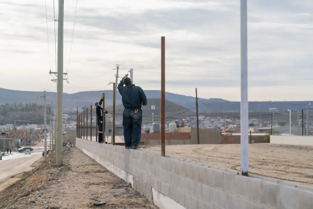 Obras de construcción en el barrio 30 de Octubre con operarios trabajando en el cerramiento perimetral.
