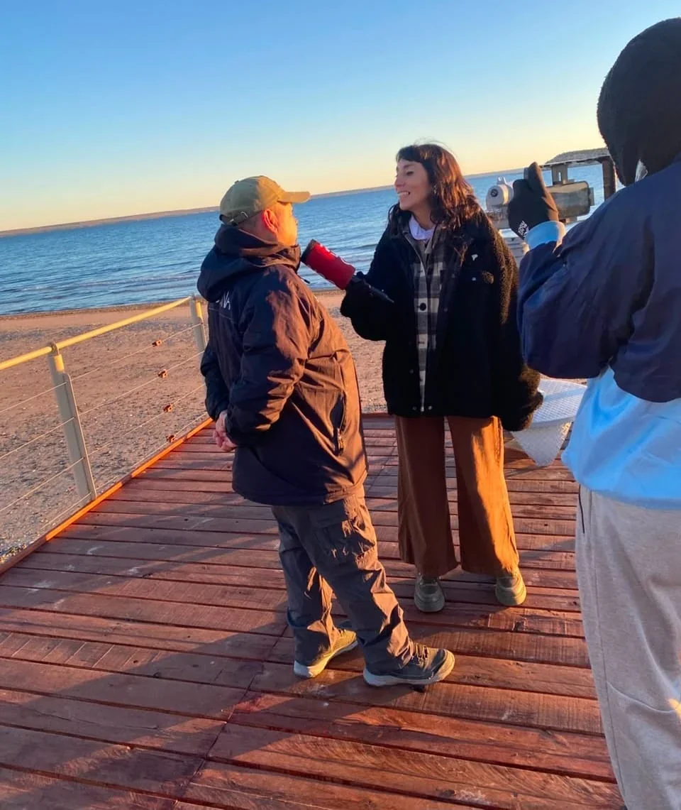 Periodista de C5N entrevistando a un residente en un muelle de Puerto Madryn durante la temporada de ballenas 2026.