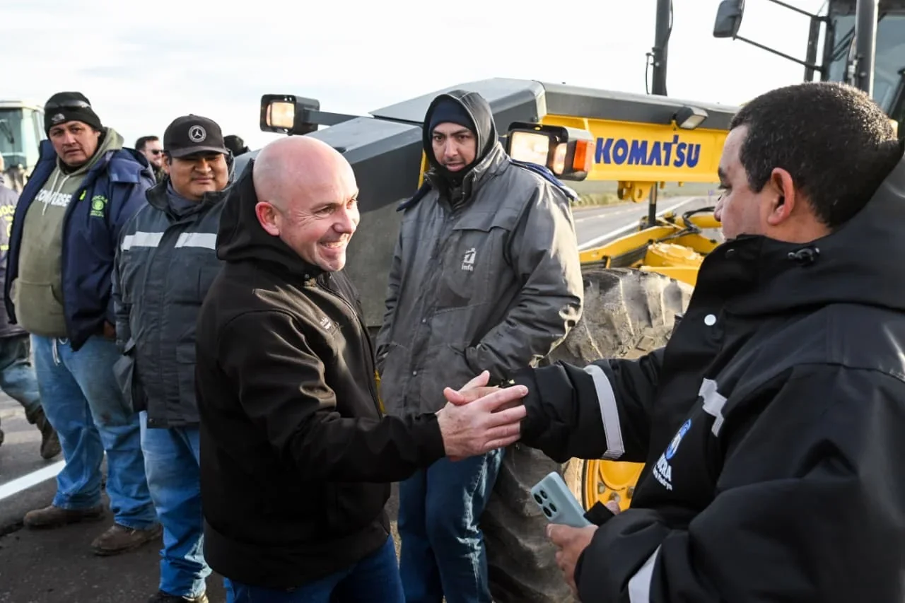 El intendente Gustavo Sastre saluda a un trabajador junto a maquinaria vial en la inauguración del asfalto en Puerto Madryn.