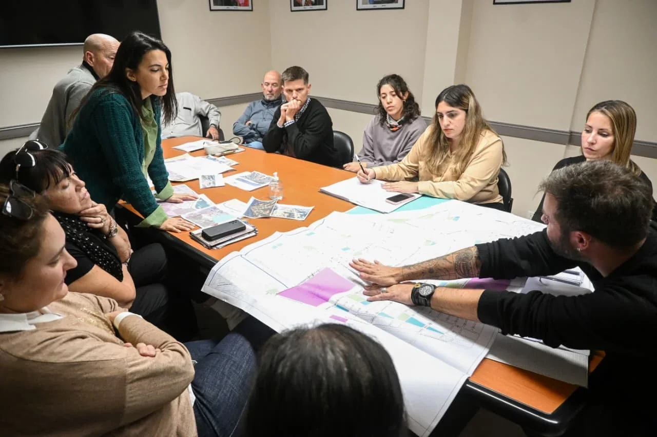 Reunión entre el secretario Tommaso Grioni, técnicos municipales y arquitectos analizando planos urbanos sobre una mesa.