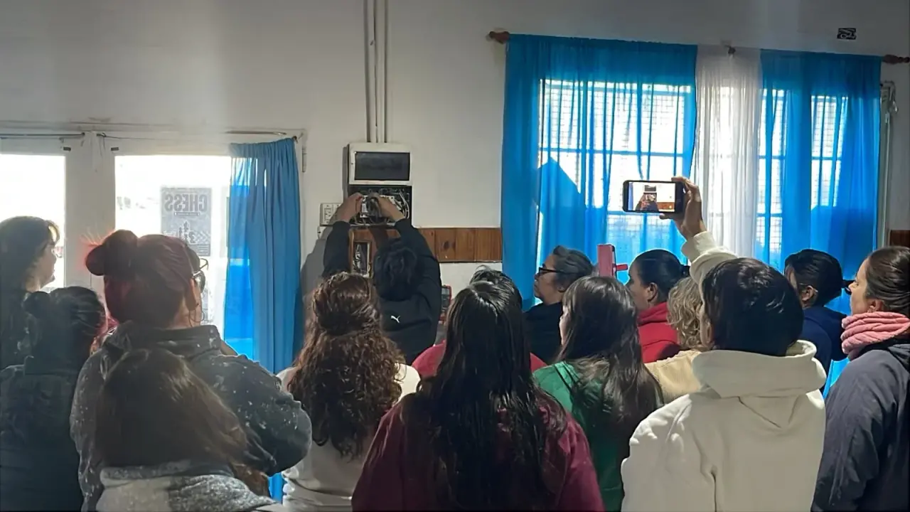 Grupo de mujeres en Rawson observando una demostración práctica de electricidad en un aula.