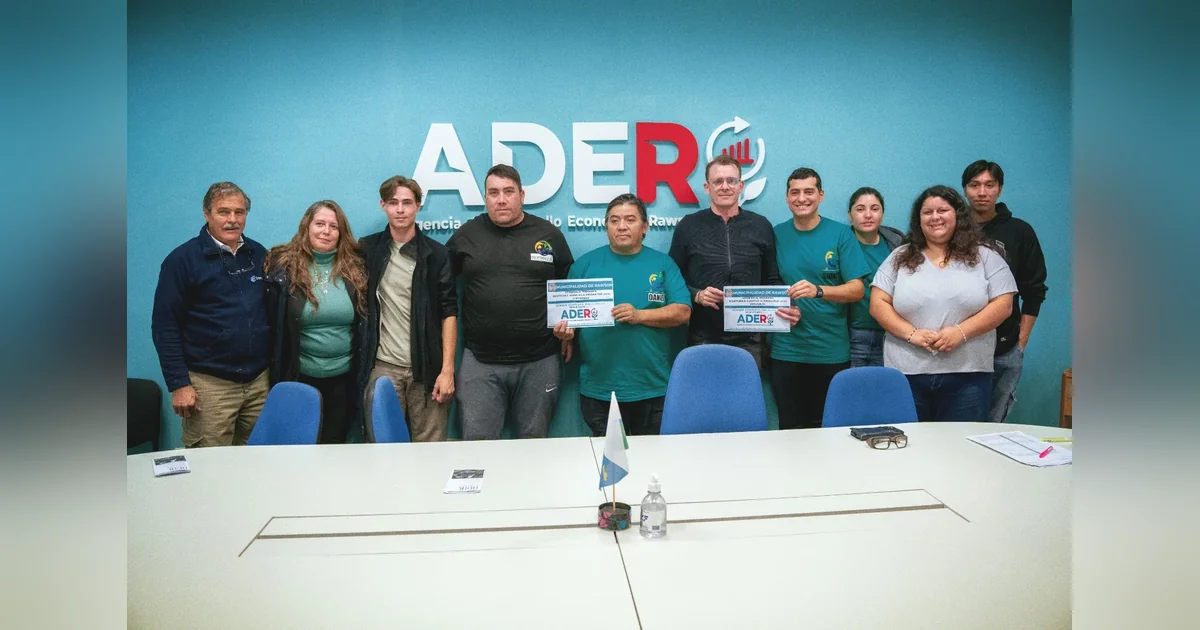 Rawson: Agencia de Desarrollo entregó nuevas credenciales a productores locales Grupo de personas posando frente al logo de ADER, donde dos hombres sostienen credenciales de productores locales.