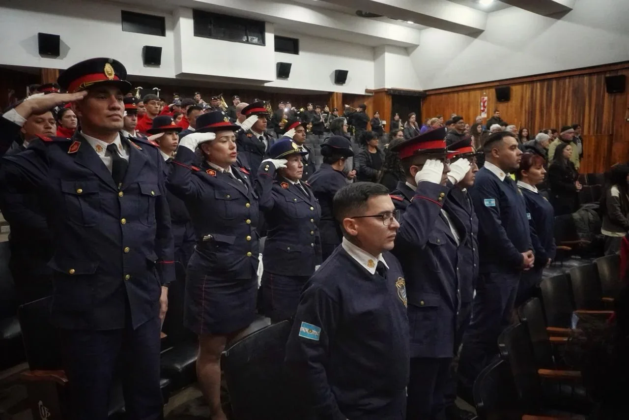 Bomberos Voluntarios de Rawson uniformados y saludando durante el acto de su 55° aniversario en el Centro Cultural.
