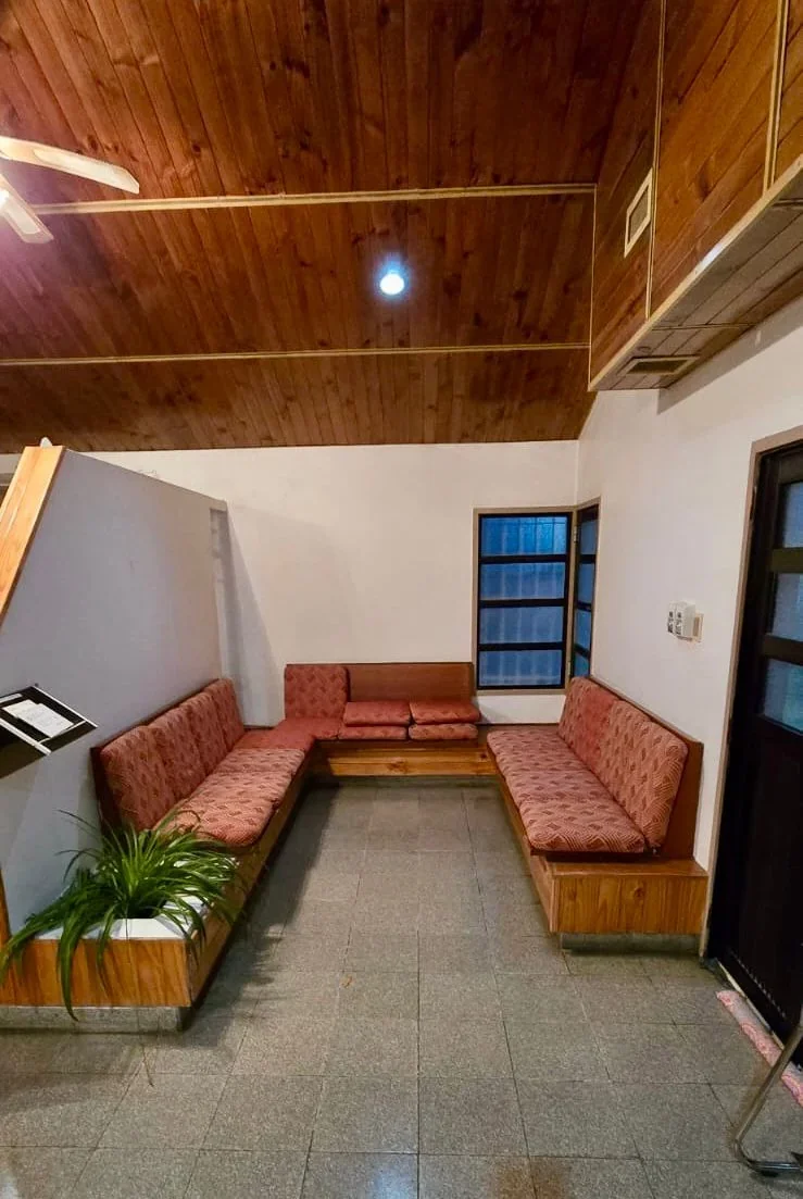 Interior de una de las salas del Servicio Solidario de Sepelio de la Cooperativa de Rawson con sofás rojos y techo madera.