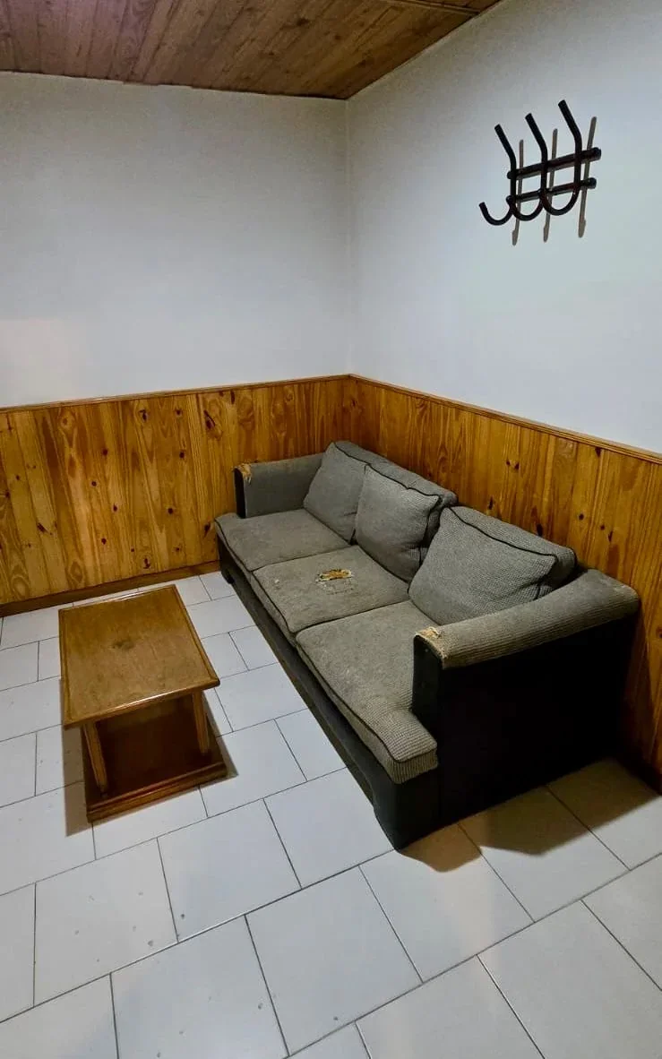 Interior de una de las salas del Servicio Solidario de Sepelio en Rawson con un sofá gris y mesa de madera.