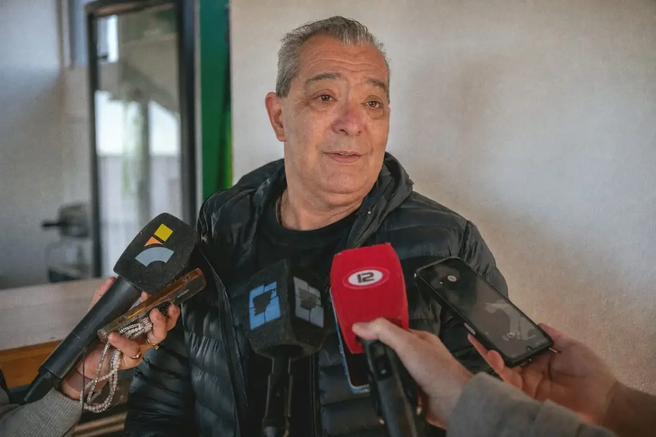 Daniel Tamame, secretario de Educación de Rawson, brindando declaraciones ante varios micrófonos y un teléfono móvil.