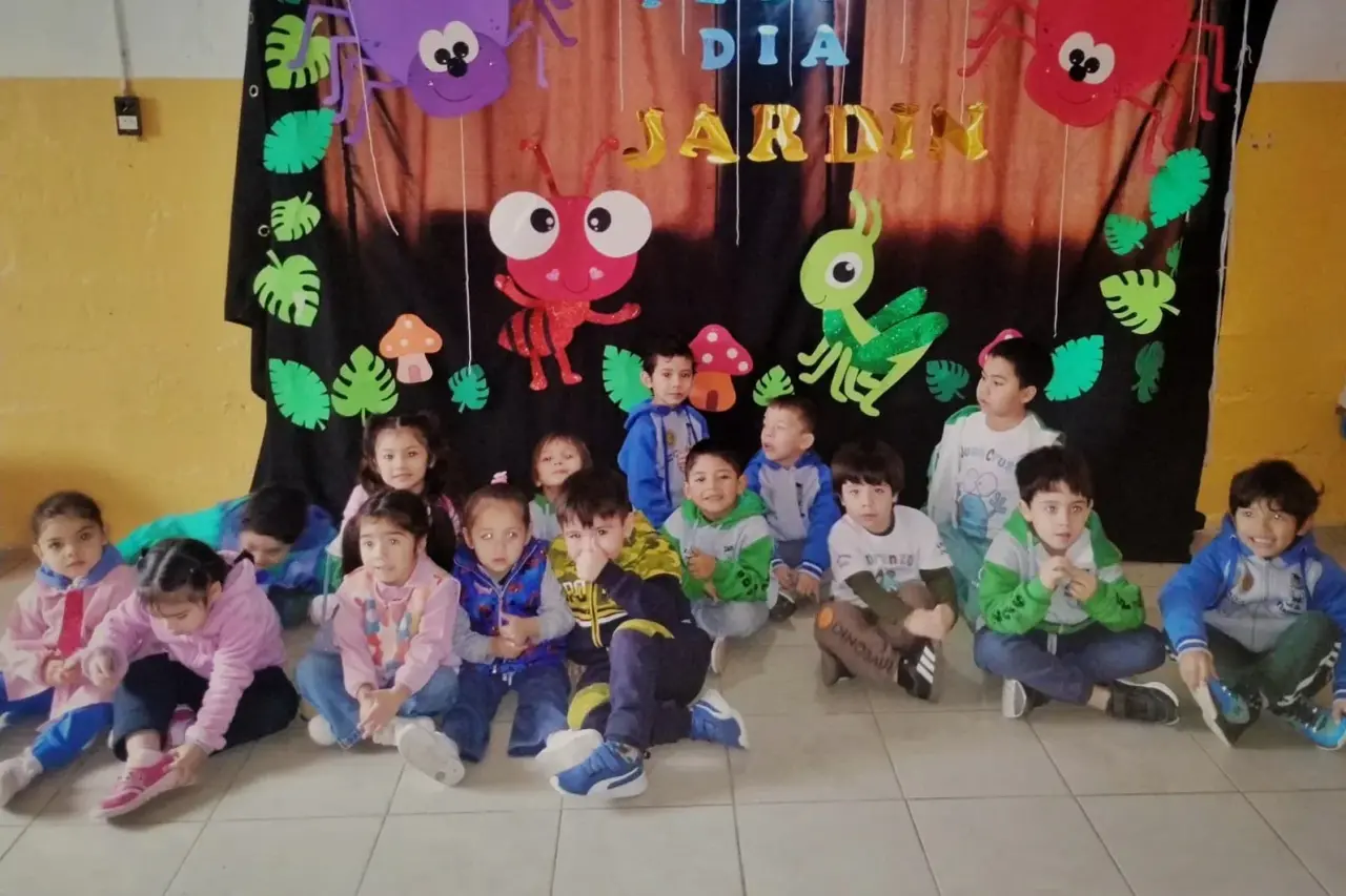 Niños y niñas de los Jardines Municipales de Rawson posando frente a un decorado temático del mundo de los bichos.
