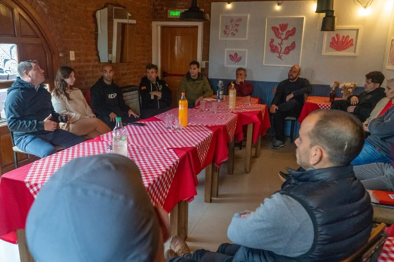 Reunión entre el intendente Damián Biss, funcionarios y gastronómicos de Rawson alrededor de mesas con manteles rojos.