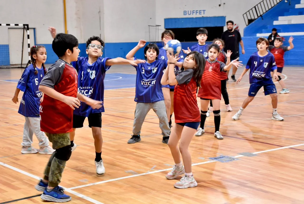 Niños y niñas jugando un partido de handball infantil en el Gimnasio Municipal N.º 1 de Trelew.