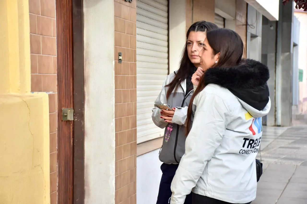 Dos agentes de Atención Ciudadana de Trelew con camperas institucionales recorriendo una zona urbana.