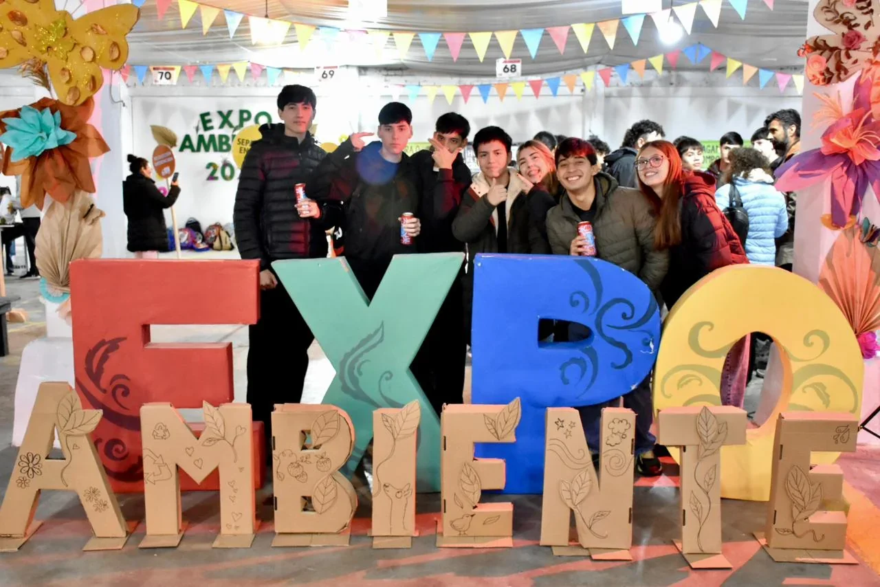 Grupo de estudiantes posando detrás de letras gigantes que forman el texto 'EXPO AMBIENTE' en la Sociedad R